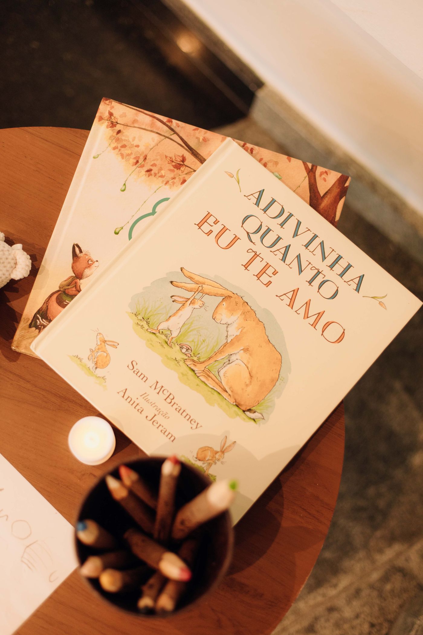 Children's picture books and wooden pencils on a table by candlelight