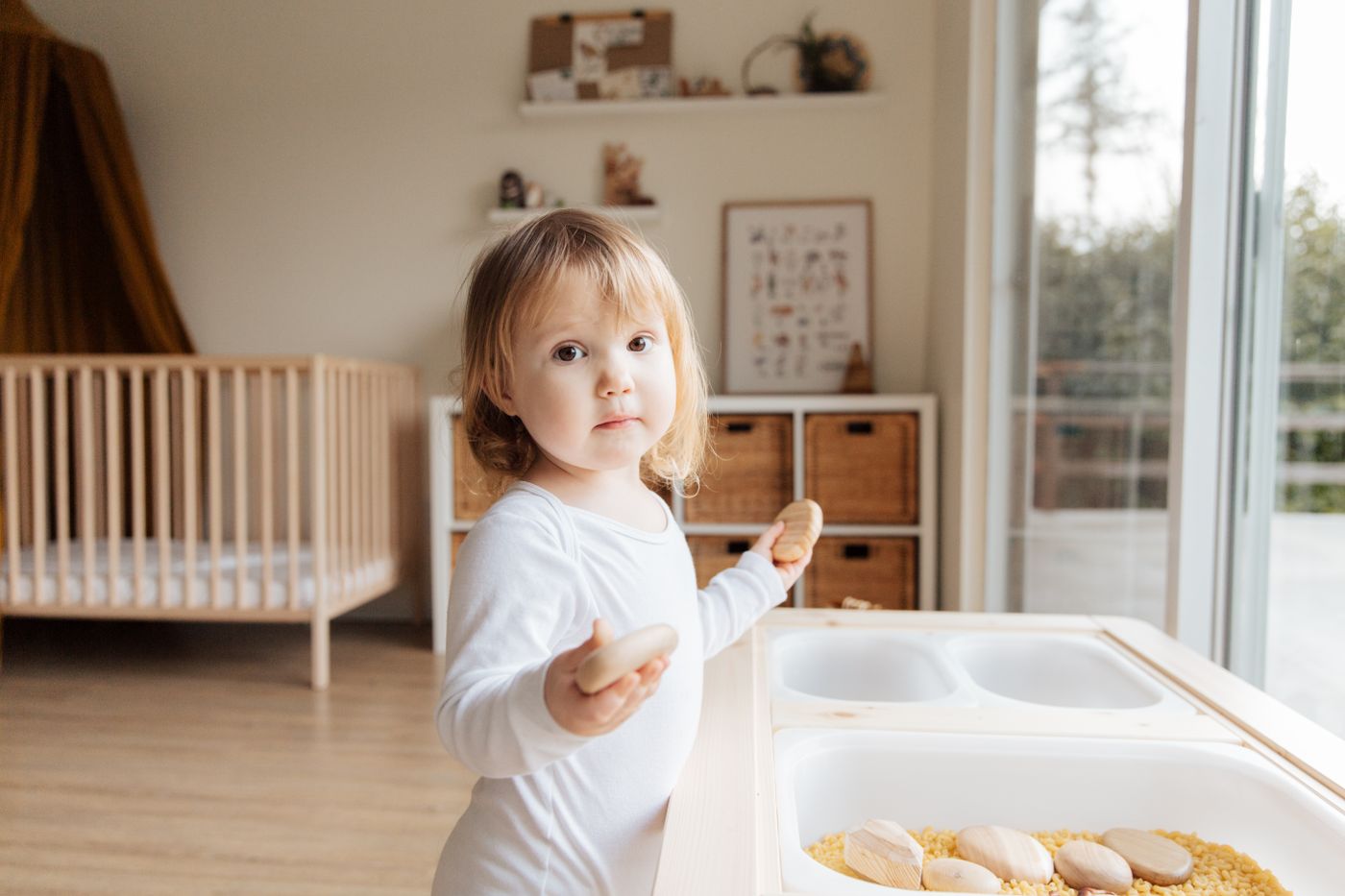 Toddler standing at a low table, helping with a tray