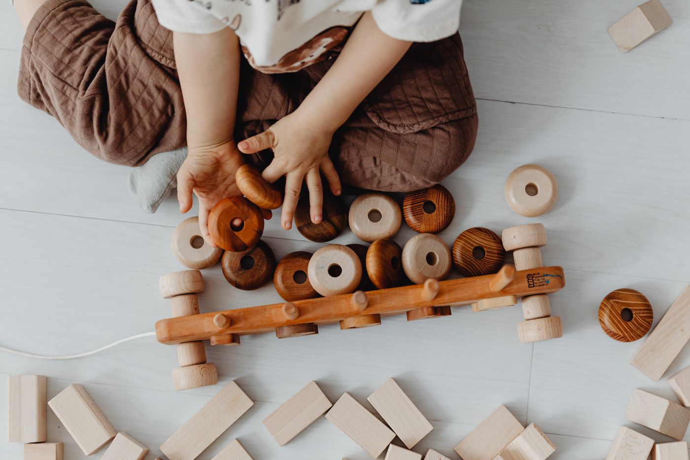 Toddler stacking smooth wooden rings on the floor