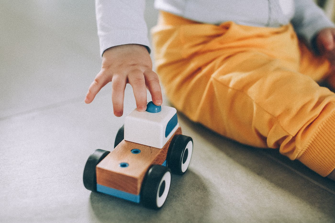 Toddler playing on the floor with a small wooden car